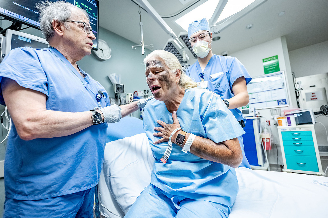 A physician assess a distressed simulated patient with moulage injuries during a Mass Casualty Incident drill at Texas Health Presbyterian Hospital Dallas - capturing the intensity and human drama of emergency preparedness training.
