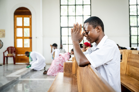 Man praying during Sunday morning church service at Sacré Cœur Medical Center in Guinea, West Africa, where faith and community are part of the mission.