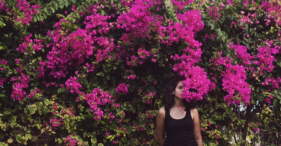 Young woman standing between fuchsia bougainvillea flowers