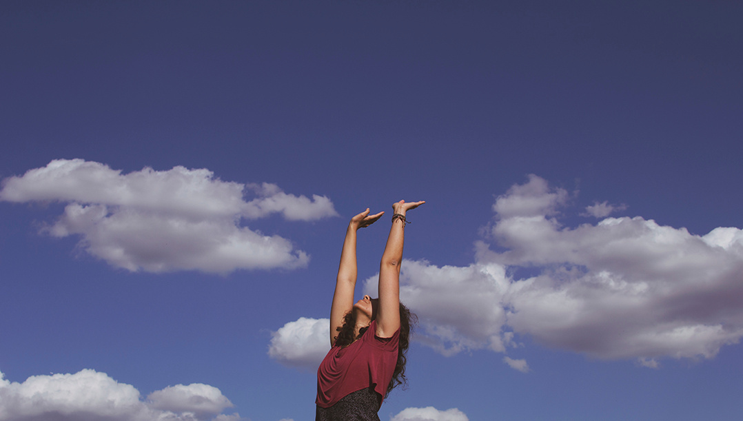 Young woman spreading her arms towards a wide sky