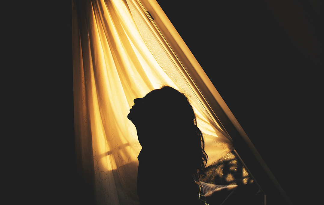 Silhouette of a young woman against golden hour light