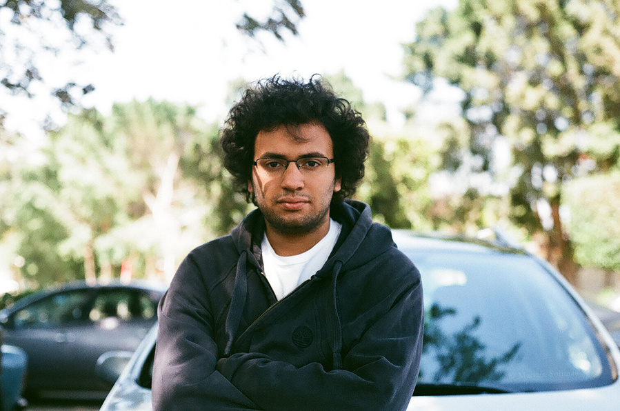 Analog portrait of young man in front of car