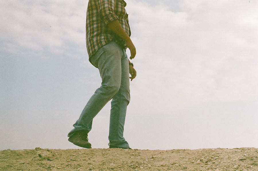 Spontaneous analog photograph of young man in motion on top of sandy surface