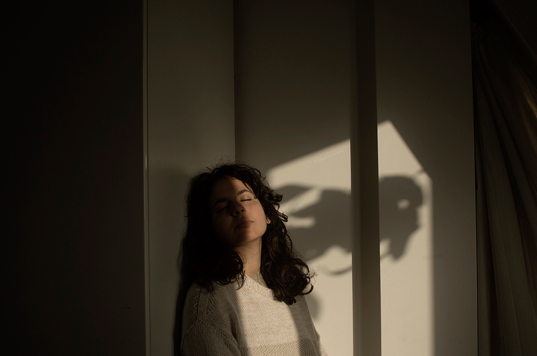 Emotional indoor self portrait of young woman during golden hour