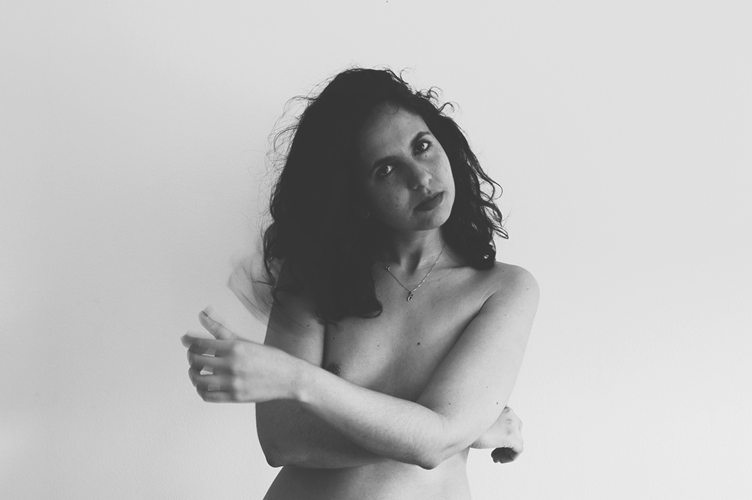 Black and white self portrait of upper nude young woman with a challenging look