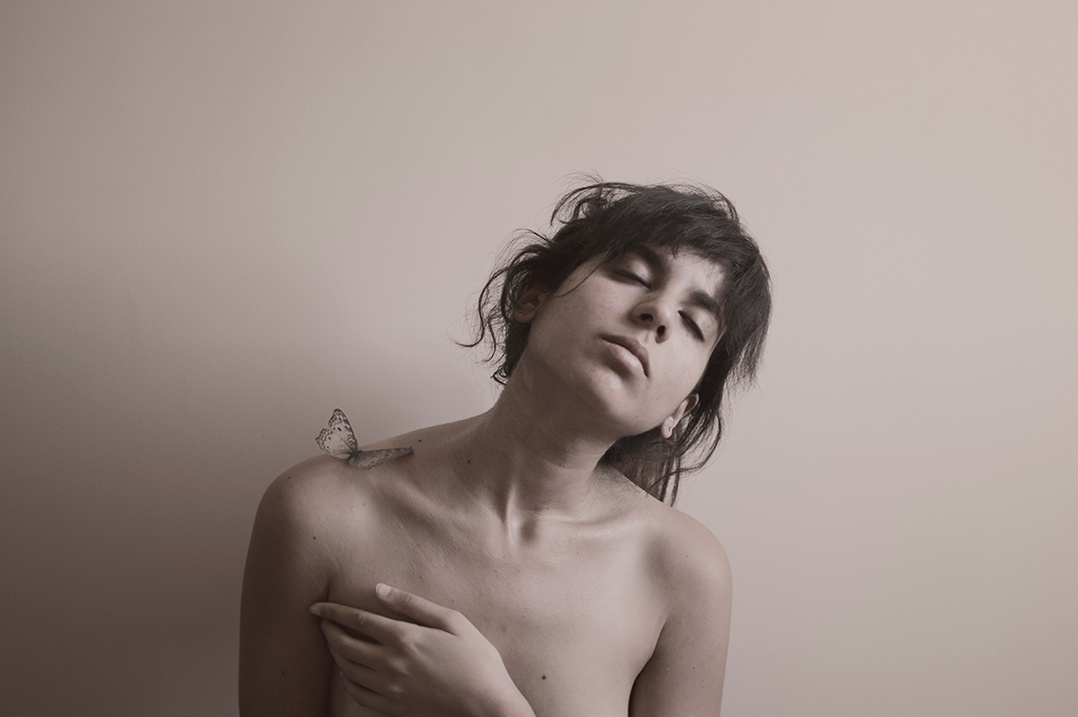 Soft self portrait of young woman with butterfly on shoulder