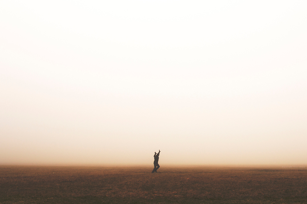 Dreamy photograph of man running on a foggy empty field 