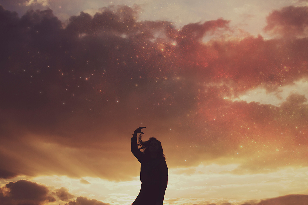 Silhouette of a young woman against a colorful sunset sky