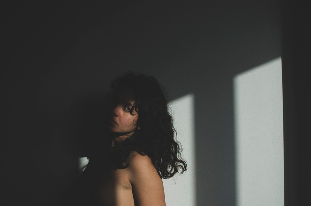 Emotional indoor self portrait of young woman during golden hour