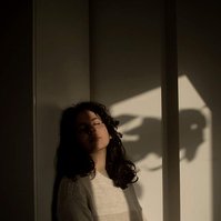 Emotional indoor self portrait of young woman during golden hour