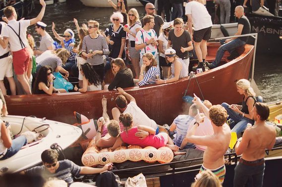 People celebrating on their boats during Amsterdam Gay Pride / Canal Parade in 2015.
Feiernde Menschen auf ihren Booten während der Amsterdam Gay Pride / Canal Parade im Jahr 2015.