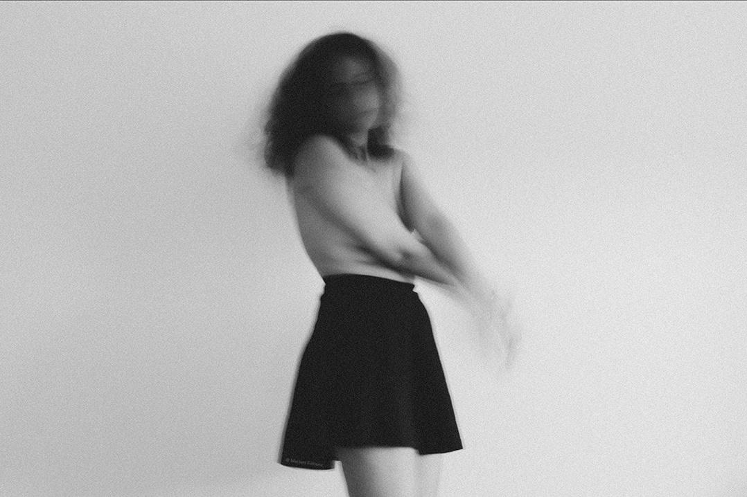 Black and white self portrait of young female in black skirt and nude upper body