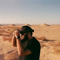 Analog photograph of young man with black apparel in the desert