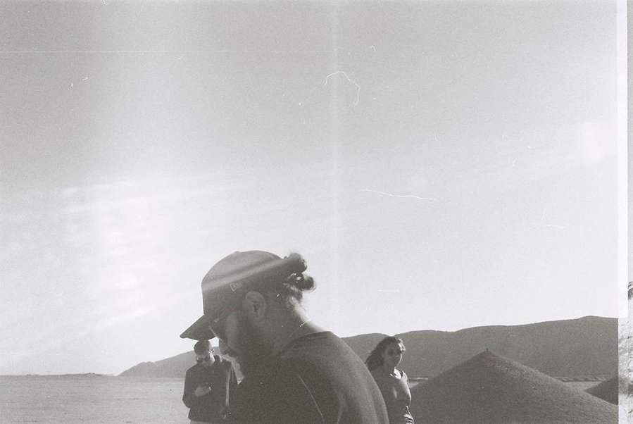 Analog black and white photograph of young man with black apparel in the desert