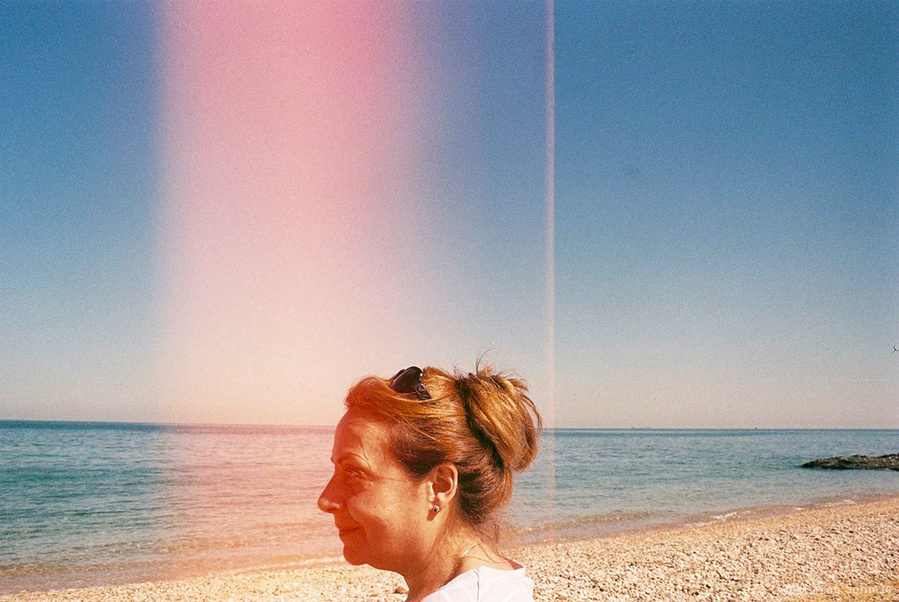 Analog portrait of woman by the beach with red light leak