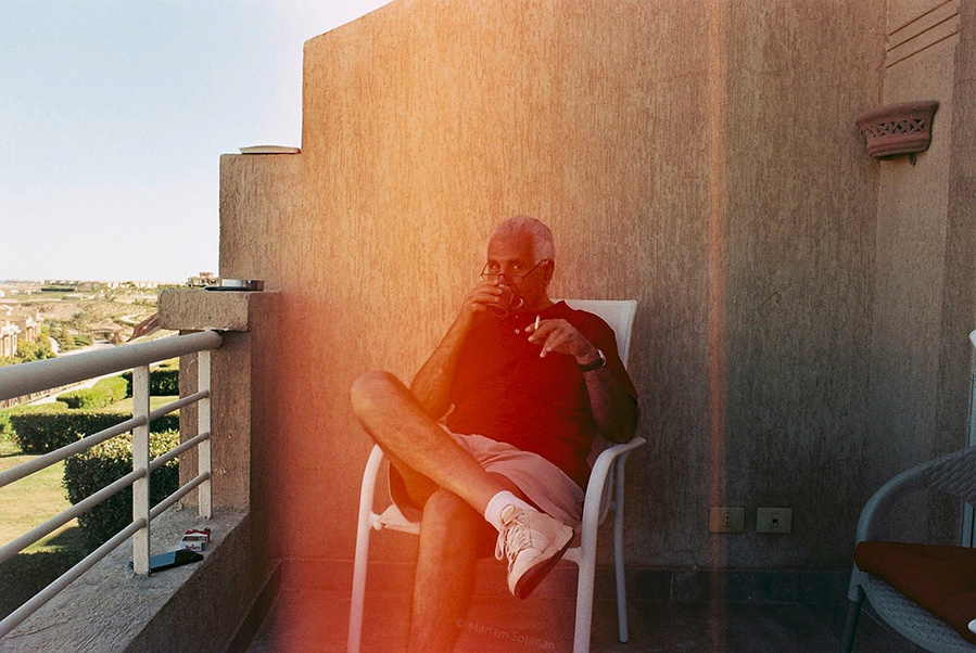 Analog photograph of man with coffee and cigarettes and red light leak