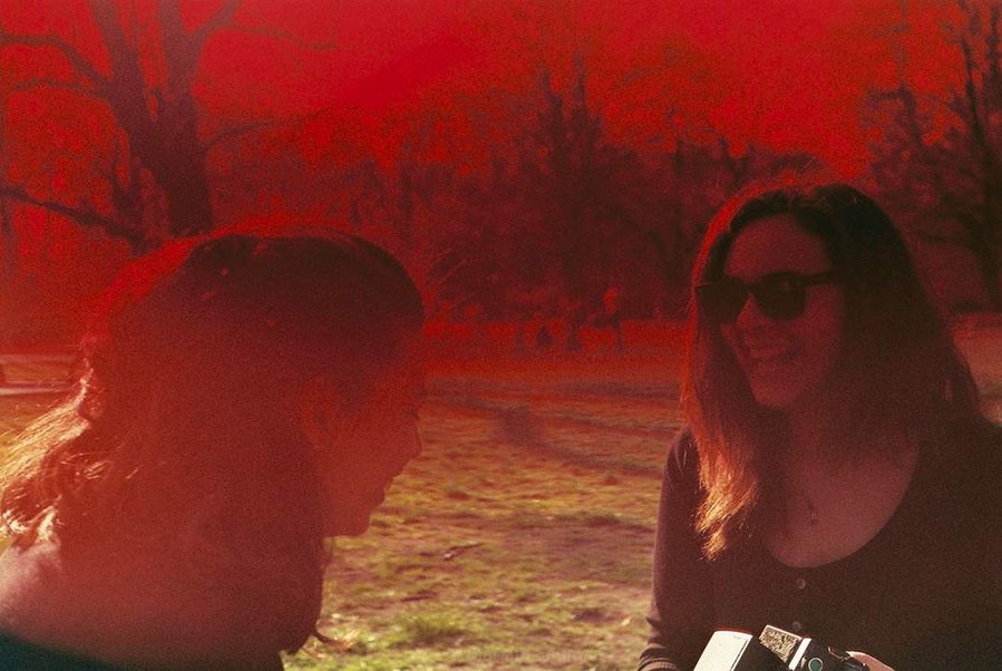 Analog photograph with red filter of two girls laughing at Treptower Park in Berlin