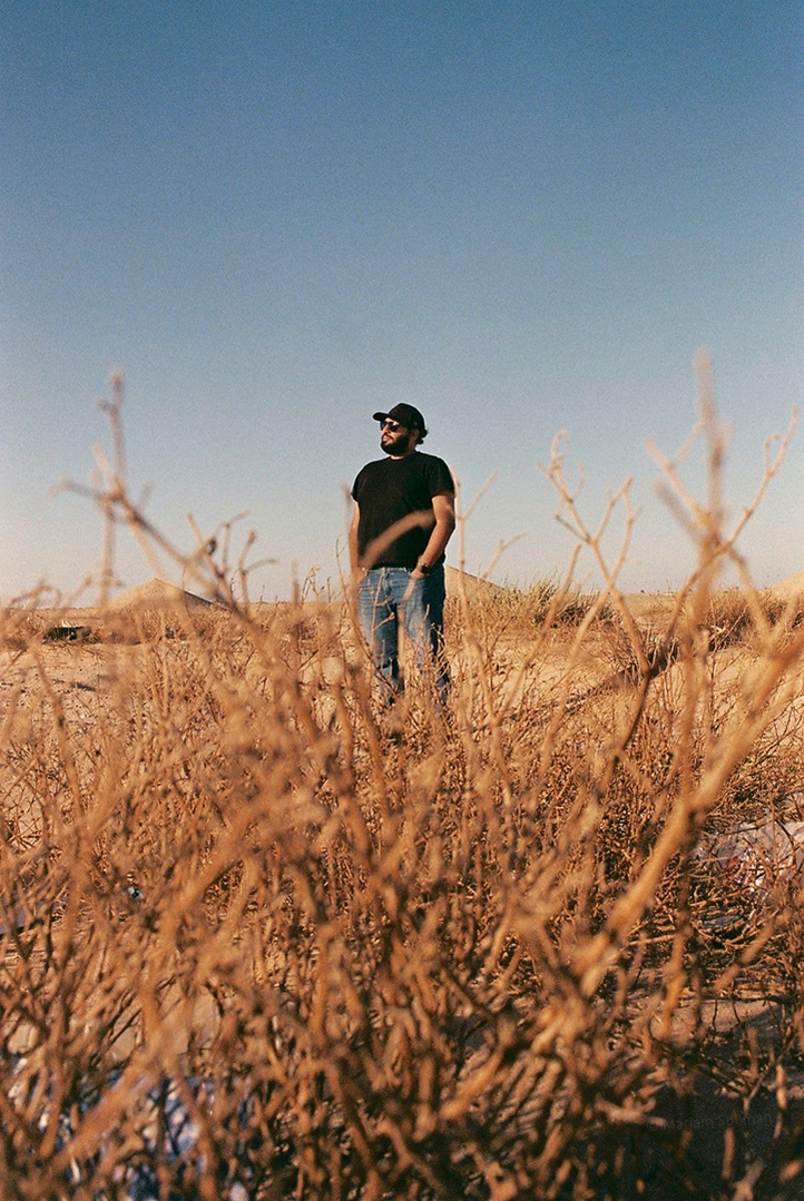 Analog photograph of young man with black apparel in the desert
