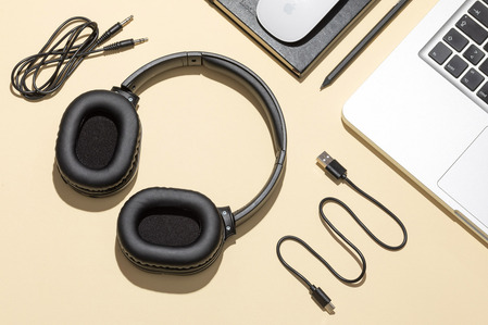 headphones on yellow background with laptop, cables and notebook