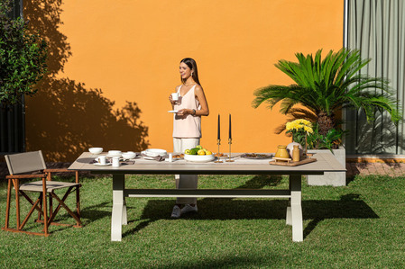 outdoor furniture table and chair on grass in a garden with a young women enjoying a cup of beverage