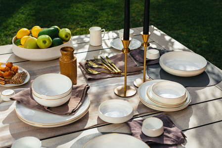 detail of outdoor furnitures, dining table and wooden fabric chair on grass, plares,lemons