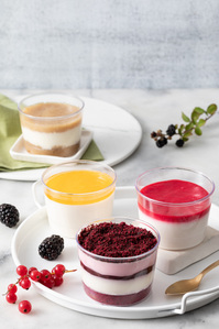 A table with cups of dessert and a spoon.

