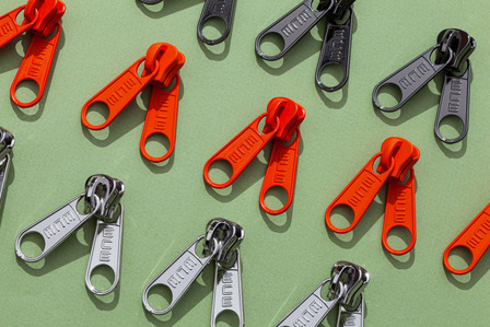 orange, black and grey zippers on green background