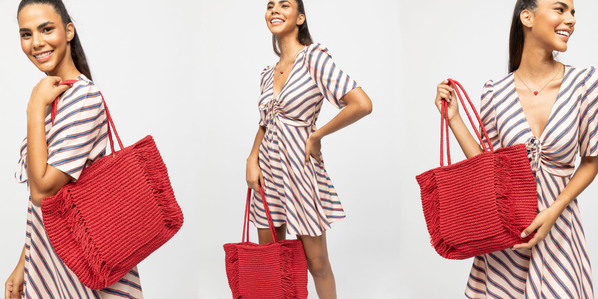 photo model holding women&#x27;s bag in a white black striped dress on plain background