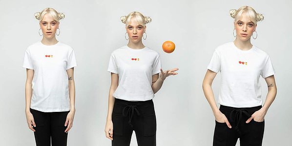 photo model in black pants and white shirt holding an orange on plain white background