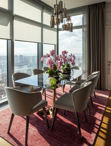 interior with dining table and chairs, decorated with pink orchids and red carpet, city view