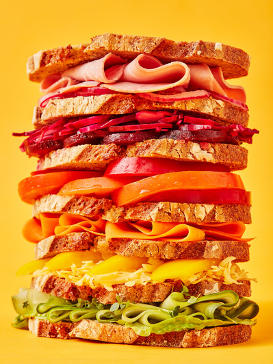 A stacked rainbow sandwich shot on a bright yellow background, perfect for editorial and restaurant food photography, shot by food photographer, Sid Ali