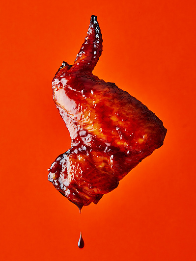 A floating chicken wing on bright orange background, perfect for editorial, advertising and restaurant food photography, shot by food photographer, Sid Ali