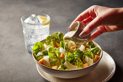 a cesar salad with a hand pouring the dressing on top, perfect for editorial, advertising and restaurant food photography, shot by food photographer, Sid Ali