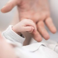 parent holding hand of newborn baby