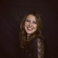 Professional studio portrait of a woman wearing a black and gold dress against a black studio backdrop