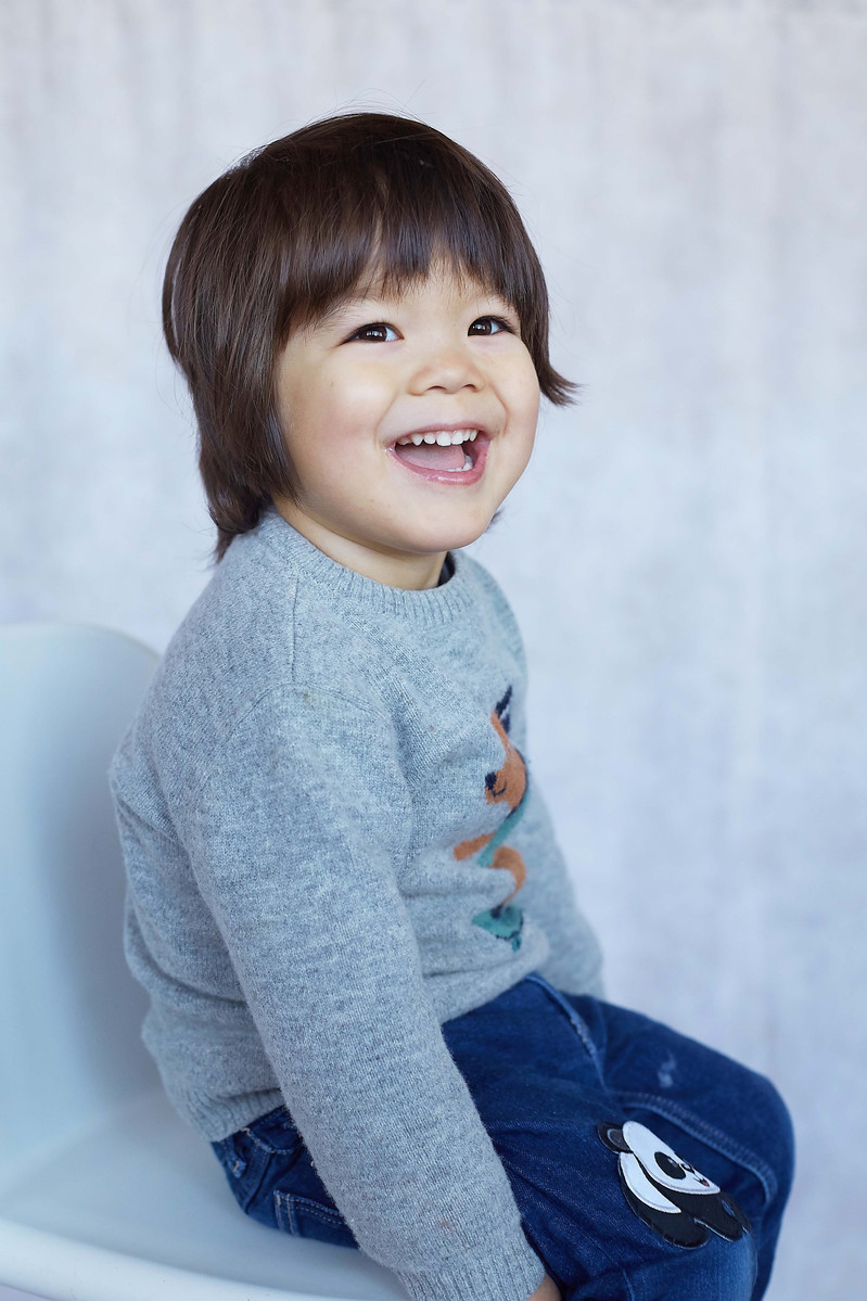 Toddler boy sitting on a chair in a photography studio