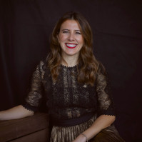 Professional studio portrait of a woman wearing a black and gold dress against a black studio backdrop