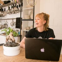 Personal branding photograph showing a woman working on a laptop in a kitchen