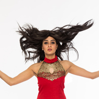 Professional photography studio portrait of a woman jumping wearing a red dress and hair flying in the air