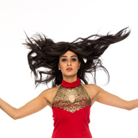 Professional photography studio portrait of a woman jumping wearing a red dress and hair flying in the air