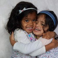 family twin girl toddlers hugging each other in studio photogrpah