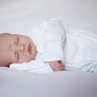 Newborn photograph of a baby wearing white on white background