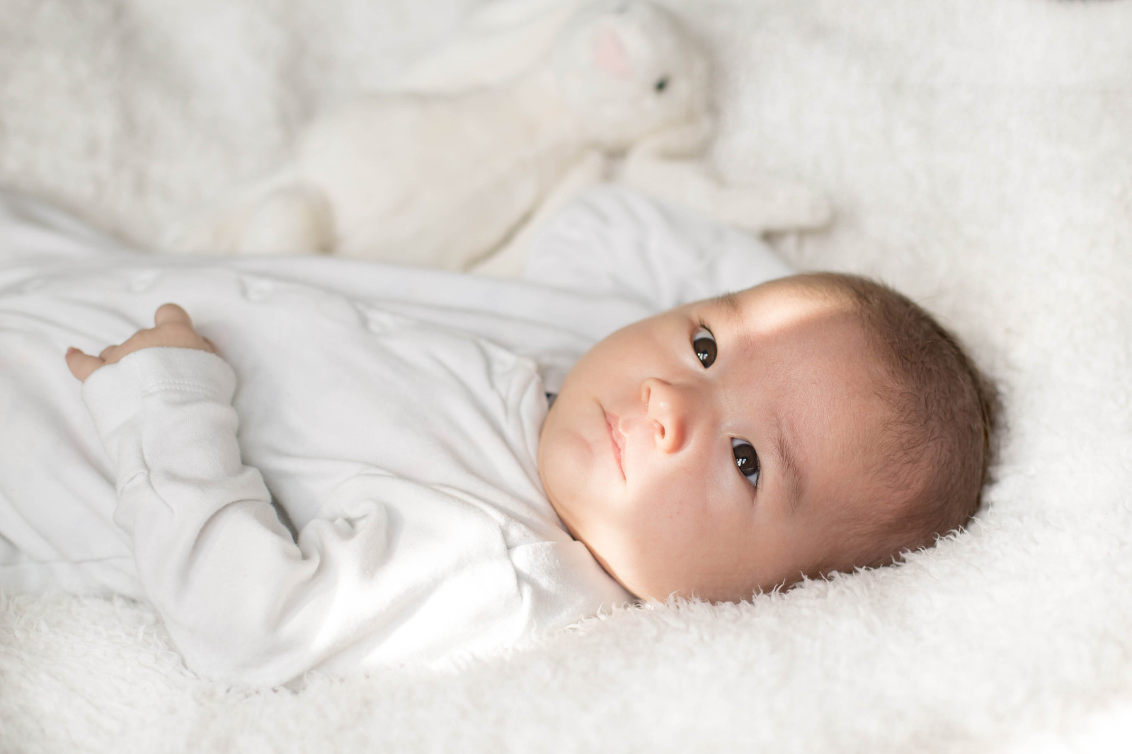 Newborn baby wearing white on a white background