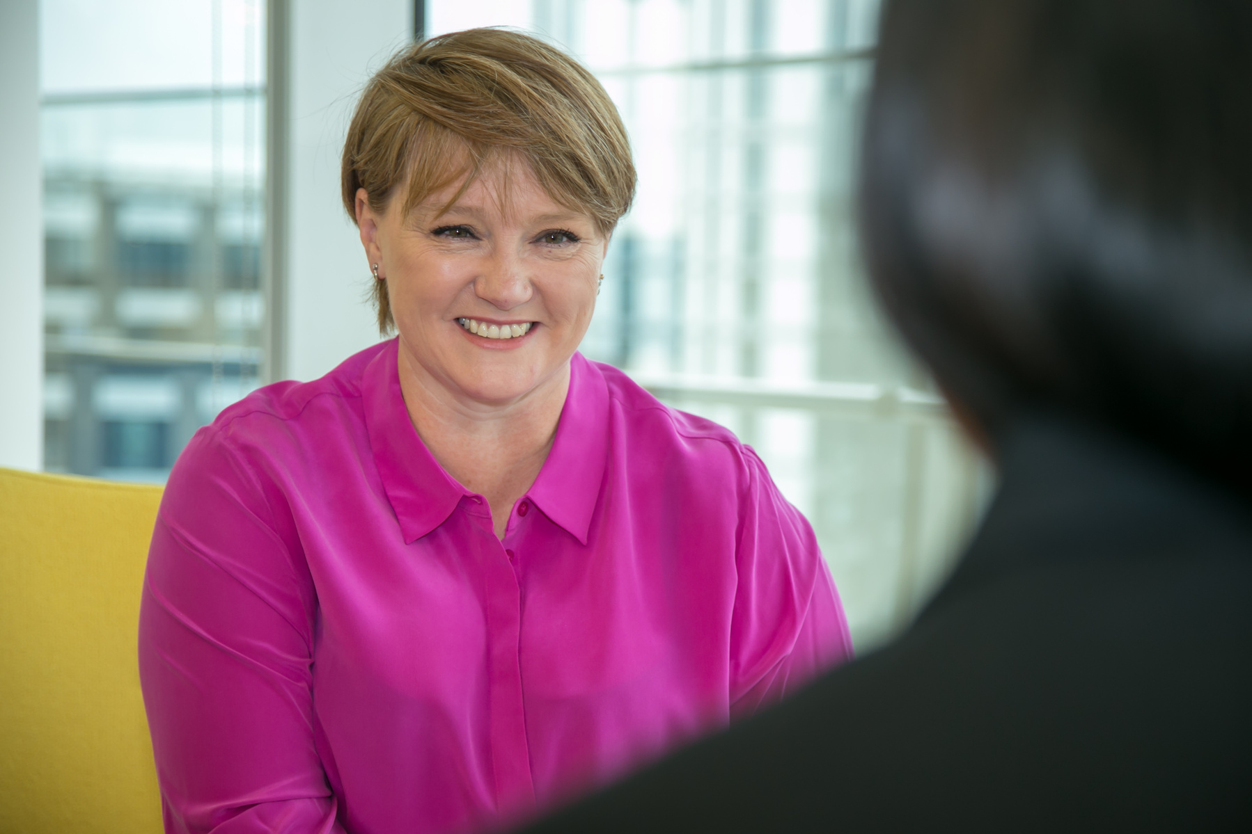 Personal Branding image of a woman wearing a pink top in an office talking to a client