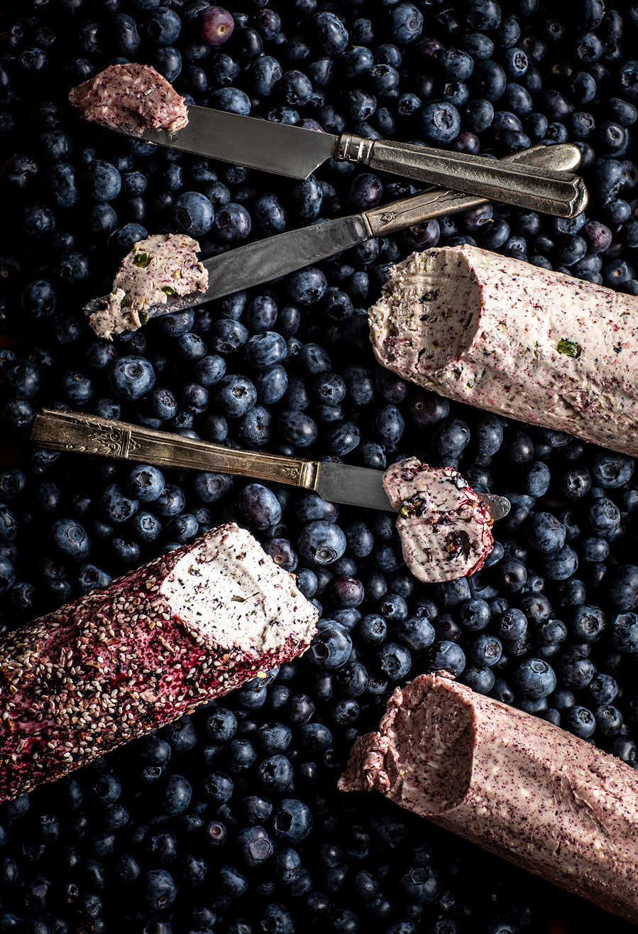 Overhead shote with blueberry cannoli and butter knives with three different blueberry fillings on the ends laying on a bed of blueberries. Images of blueberries for the blueberry council.