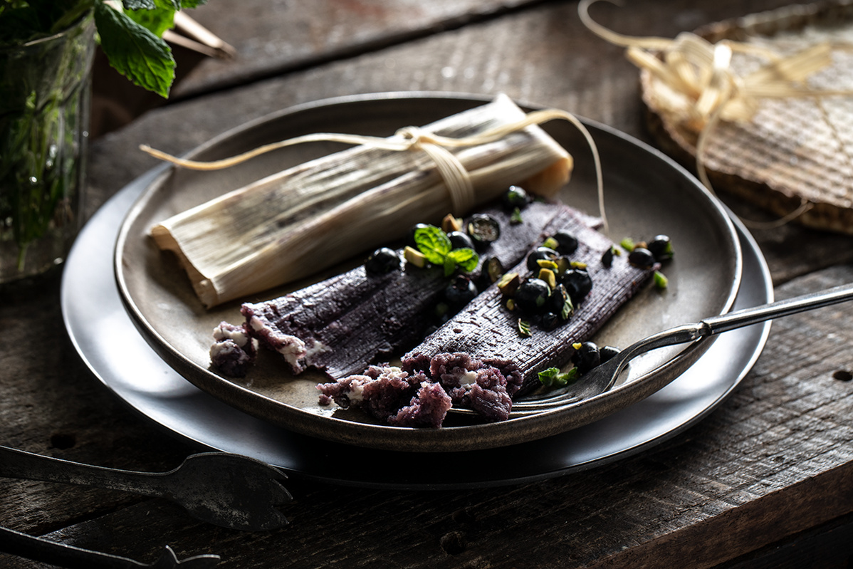 Dark and moody branding photography for Blueberry Council  with blueberry and cream cheese tamales on stacked plates and fork digging in. 