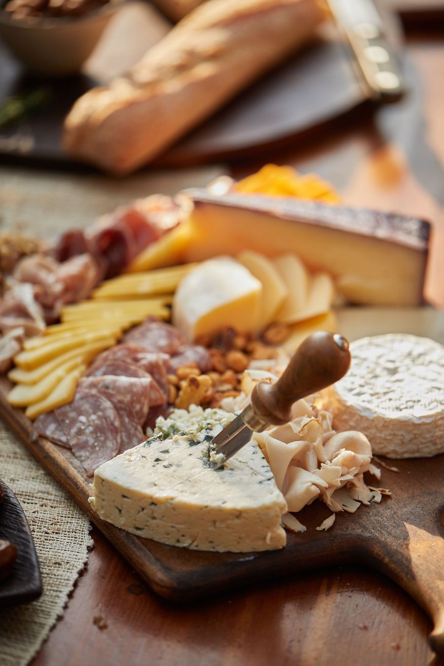 Charcuterie board on a wooden board being placed on a picnic table for an outdoor lifestyle food photography dinner party. 