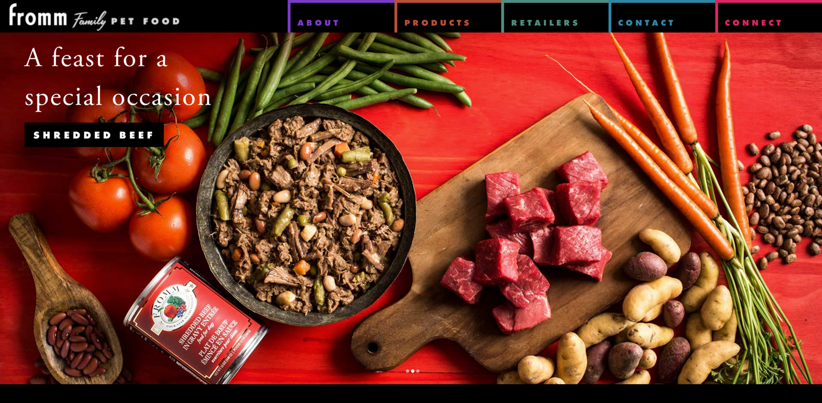 Website homepage banner with fresh ingredients on a red surface, plated wet dog food, and can of dog food. Overhead flat lay meat food photography