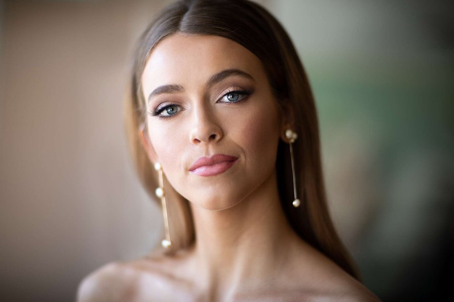 Head and shoulders photo of bride with long straight hair and dangling pearl and gold earrings