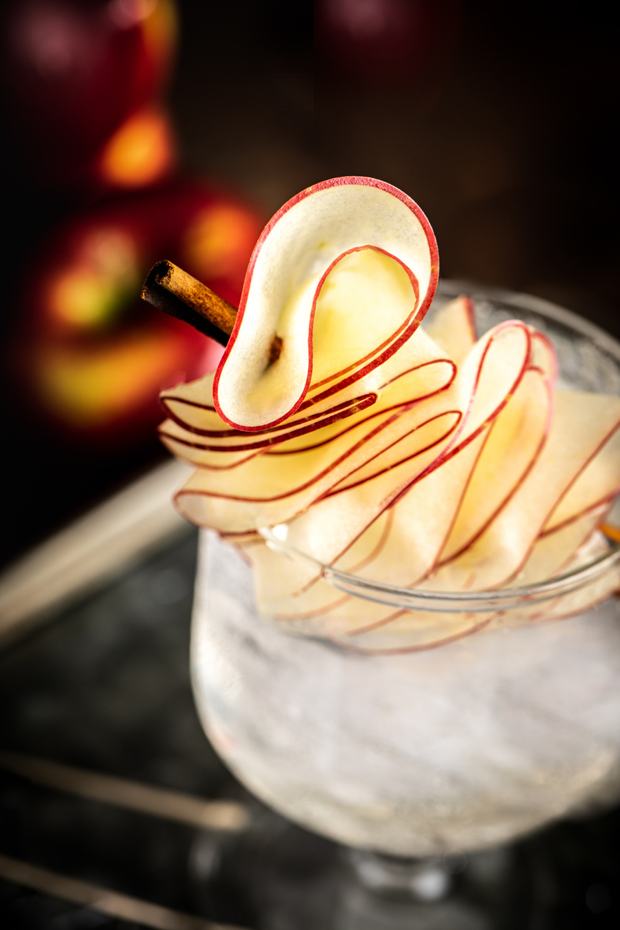 Looking into glass with ice and press seltzer with garnish of finely shaved loops of apple and a cinnamon stick. drink photography advertising photo.